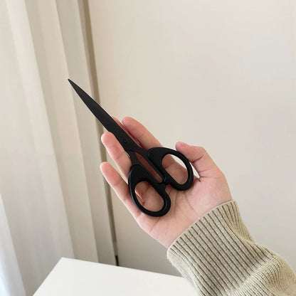 Black stainless steel scissors in the closed position, showcasing compact storage for easy portability.