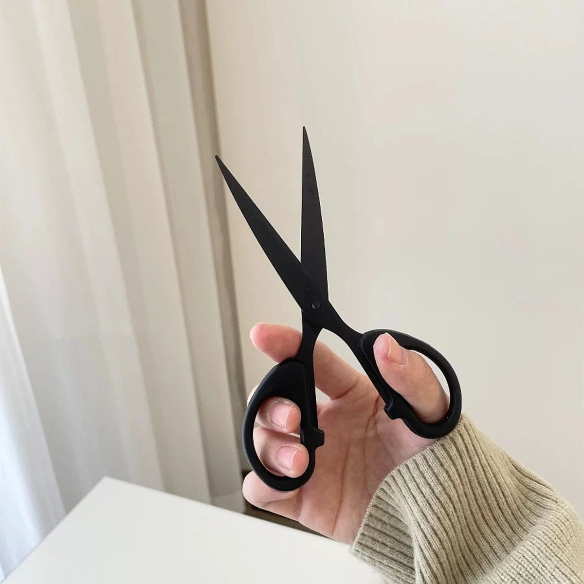 Black stainless steel scissors in the open position, designed for precise cutting during DIY crafting projects.