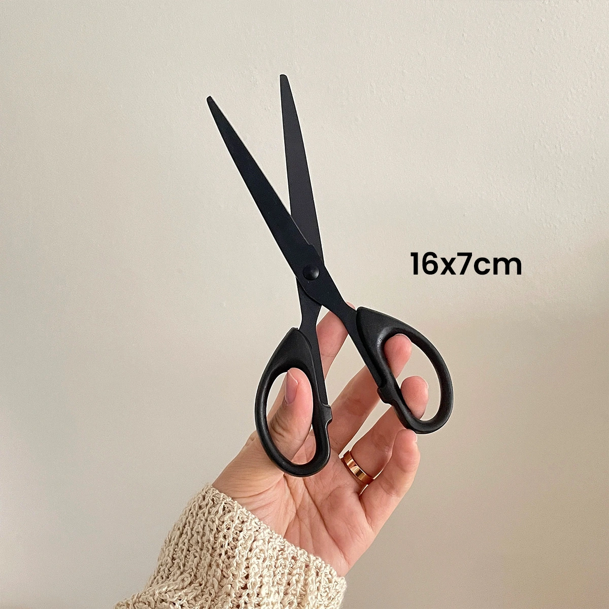 Handheld black stainless steel scissors, ideal for crafting projects, showing ergonomic grip and precision cutting.