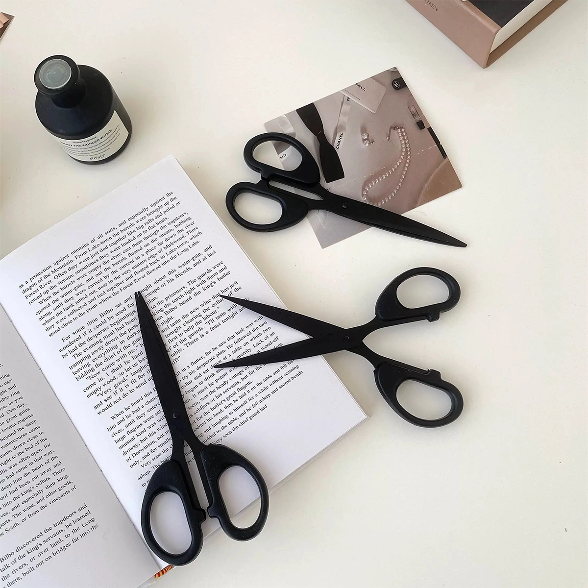 Black stainless steel scissors placed in a crafting workspace, surrounded by crafting materials like paper and tape, ready for use.